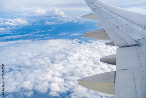 Cuadro en lienzo High altitude view of a white airplane wing over a dense layer of fluffy white clouds under clear blue sky during the day