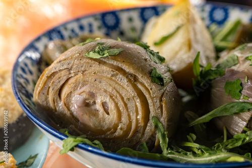 Cooked Roman-style artichokes or carciofi alla romana served in olive oil in traditional restaurant osteria in Rome, Italy