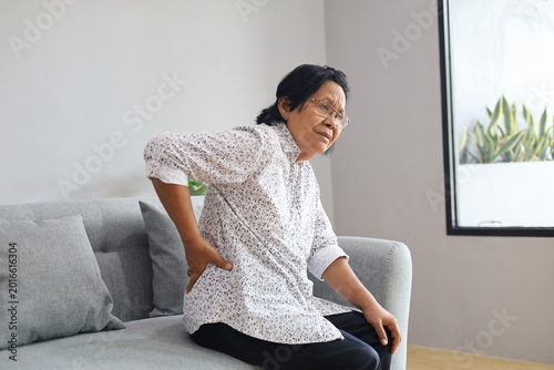 Obraz na płótnie Asian Old woman gets up off the sofa feels shooting repeated low back pain cause