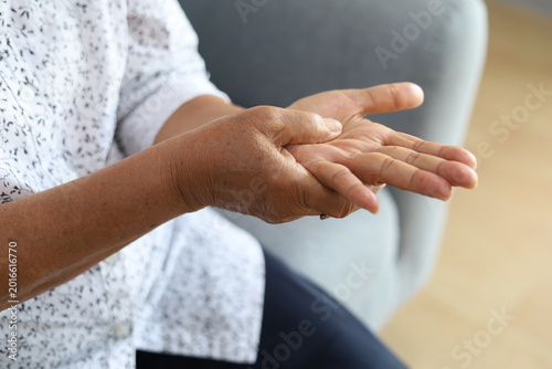 Senior woman, hands and arthritis with joint pain. Closeup of elderly female's hand massaging her palm injury or sore ache of muscle strain in living room