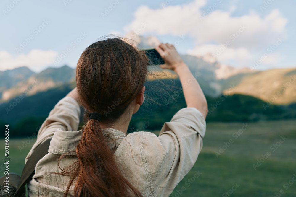 Naklejka premium Woman outdoors photographs mountains with a camera, showcasing lifestyle photography in a natural landscape, peaceful adventurous mood, focus on exploration and scenery