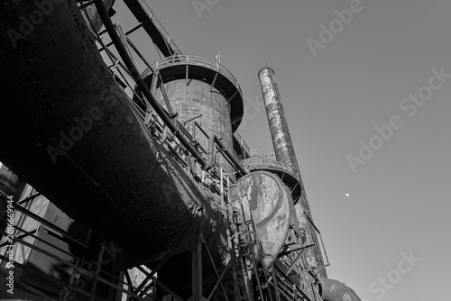 Фотография Black and white image of the rusting and peeling exterior of the storage tanks a