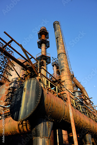 Photography Sunset and shadows on the rusting and peeling paint smoke stacks and storage tan