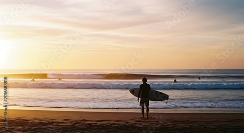 surfer walking on beach at sunset with board