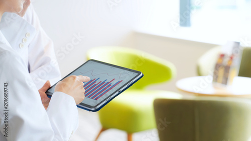 Bild auf Leinwand タブレットを見ながら会話する白衣の男女グループ