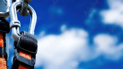 Construction safety hook close-up, sharp central carabiner against vast blurred sky, tilted angle for precision at height