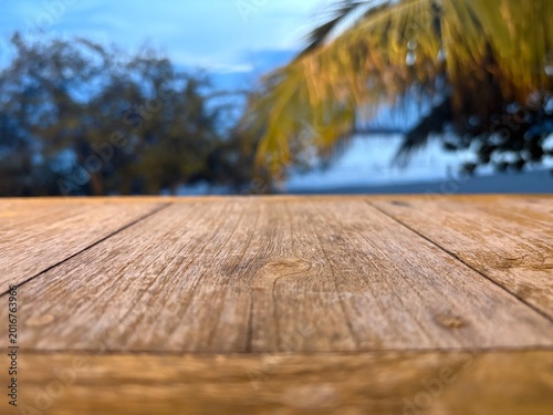 Empty wooden table top with blurred tropical beach background, palm trees, and blue sky, perfect for product display and summer vacation mockups, Chonburi, Thailand