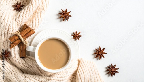 Minimal flat lay of a warm coffee cup surrounded by autumn spices and dried leaves, creating a cozy seasonal lifestyle composition.