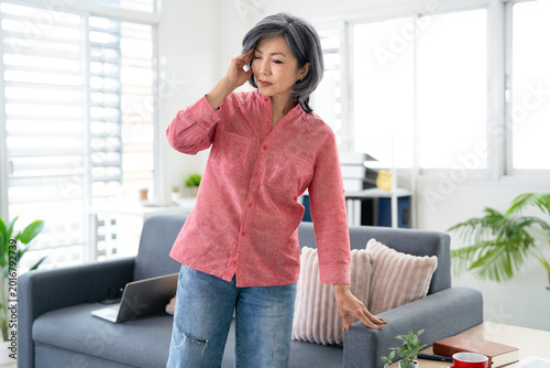Bild auf Leinwand Middle aged asian woman suffering dizzy low blood pressure standing at home