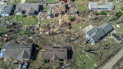 Drone view of residential neighborhood destruction after a tornado with damaged residential buildings and scattered debris.