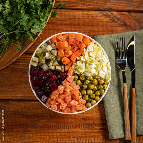 Colorful salad bowl filled with fresh vegetables and salmon on a rustic wooden table