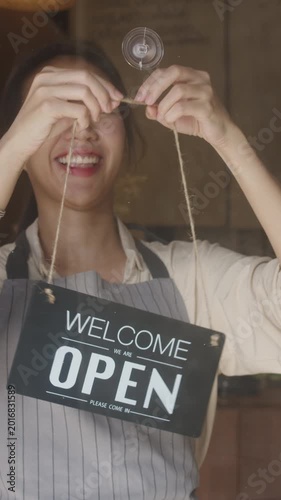 Vertical Screen : Young Asia manager girl changing a sign from closed to open sign on door cafe looking waiting for clients after lockdown. Owner small business, food and drink, business reopen again.