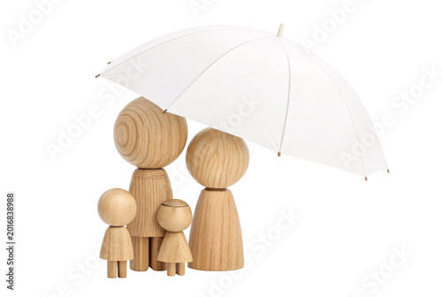 Two tall and two small rounded wooden peg dolls grouped together under a white umbrella, family protection concept photo.