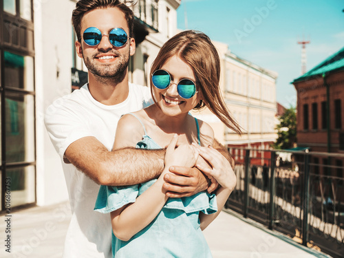 Portrait of smiling beautiful woman and her handsome boyfriend. Woman in casual summer jeans dress. Happy cheerful family. Female having fun. Couple posing on the street background in sunglasses