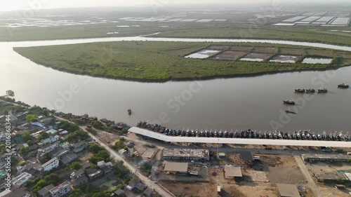 A breathtaking aerial landscape showcasing a coastal fishing harbor beside vast mangrove wetlands and waterways.