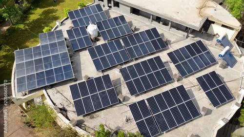 An aerial view of a modern rooftop solar power system installed on a large building. Multiple photovoltaic solar panels are arranged efficiently across the rooftop to generate clean, renewable energy.