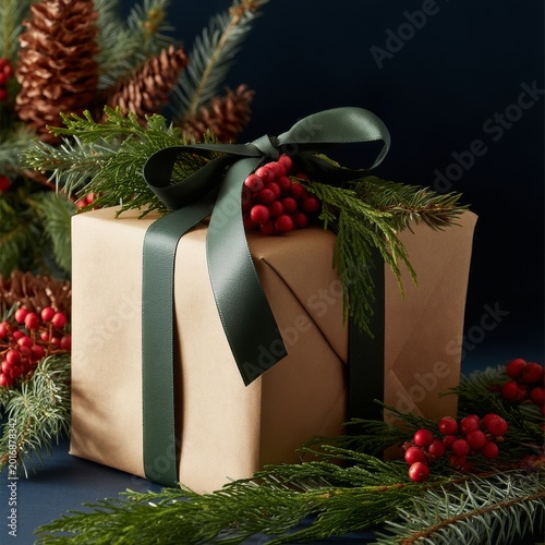Gift Box With Red Ribbon and Green Decorations on Dark Background