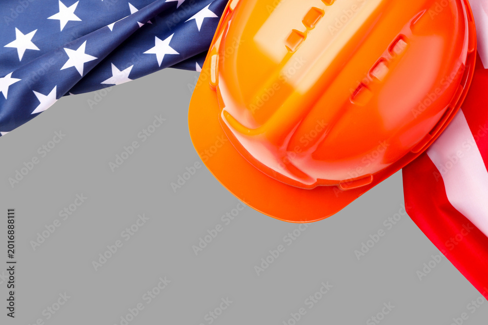 Fototapeta premium Hard hat rests near American flag showing Labor Day spirit