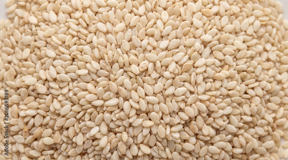 Fototapeta premium A vibrant close-up of a pile of white sesame seeds showcasing their smooth texture and pale color creating a clean and bright natural background
