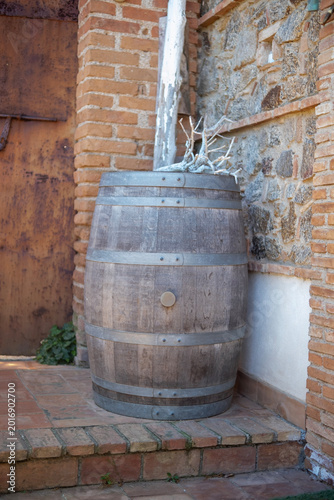 Wooden wine barrel leaning against a brick wall on a farm porch. The photo was taken near the seaside village of Rodia, Sicily, in Southern Italy