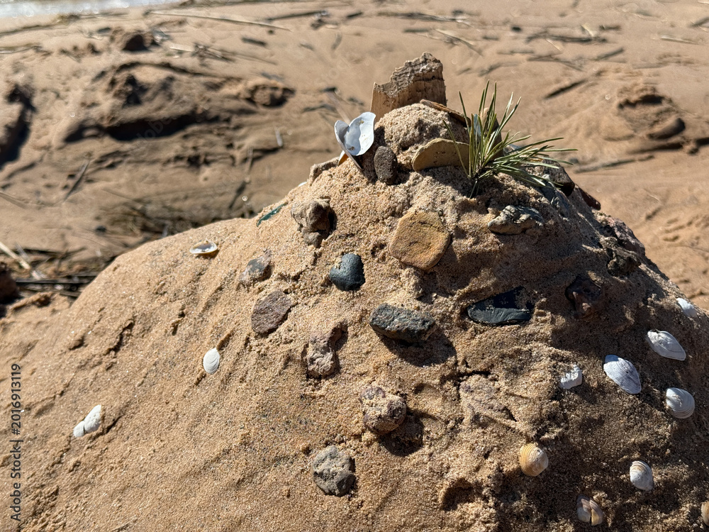 Obraz premium Creative Sand Sculpture With Shells and Stones on Beach