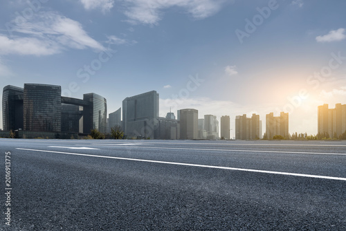 Asphalt Highway With Modern City Skyline At Sunrise