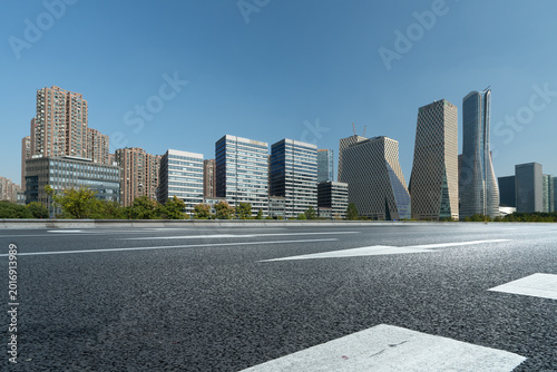 Empty Urban Road With Modern City Skyline Under Clear Blue Sky