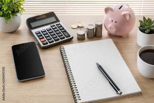 Personal Finance Budget Planning with Piggy Bank Stacks of Coins Calculator and Blank Notebook on Wooden Desk