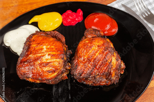 Foto Serving of well-done grilled chicken thighs with different sauces