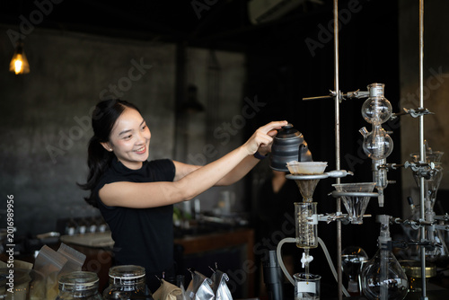 Foto Happy young Asian barista skillfully brews specialty coffee using a gooseneck ke