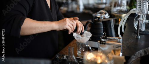 Foto A skilled barista grinds fresh coffee beans into a paper filter dripper at an up
