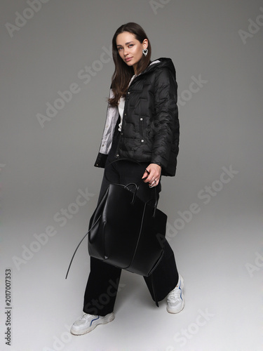Foto Stylish Young Woman in Black Winter Jacket and Large Tote Bag Poses Confidently
