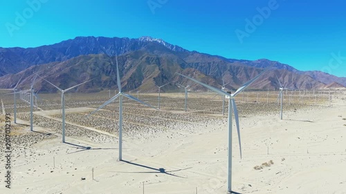 Wide aerial panorama of windmills across Palm Springs desert landscape with mountains and dry terrain scener.