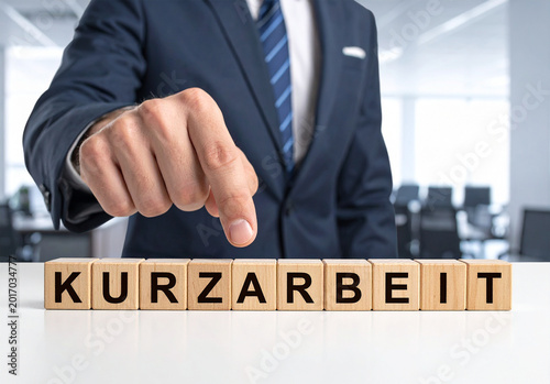 Kurzarbeit - Geschäftsmann zeigt auf den Text 