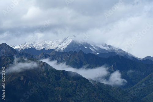 Snow-Capped Mountain Peaks Emerging Through Ethereal Clouds