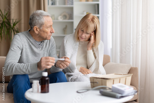 Foto Senior woman feeling unwell at home while mature husband offering her support an