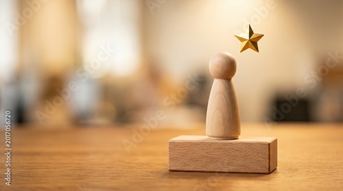 A wooden peg figure standing on a small raised podium on a warm desk with a star symbol, representing performance review and top achievement.