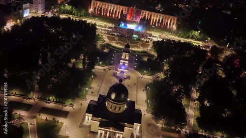 Cinematic spiraling drone descent above Chisinau Cathedral Park and concert crowd at night