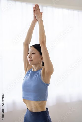 Free Download Asian Woman Performing Upward Salute Pose (Urdhva Hastasana) on Yoga Mat by Bright Window - GFXLoad