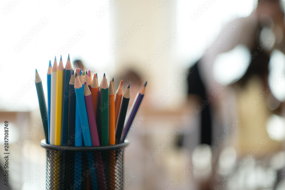 Fototapeta premium Close up of colorful pencils in a container inside a classroom