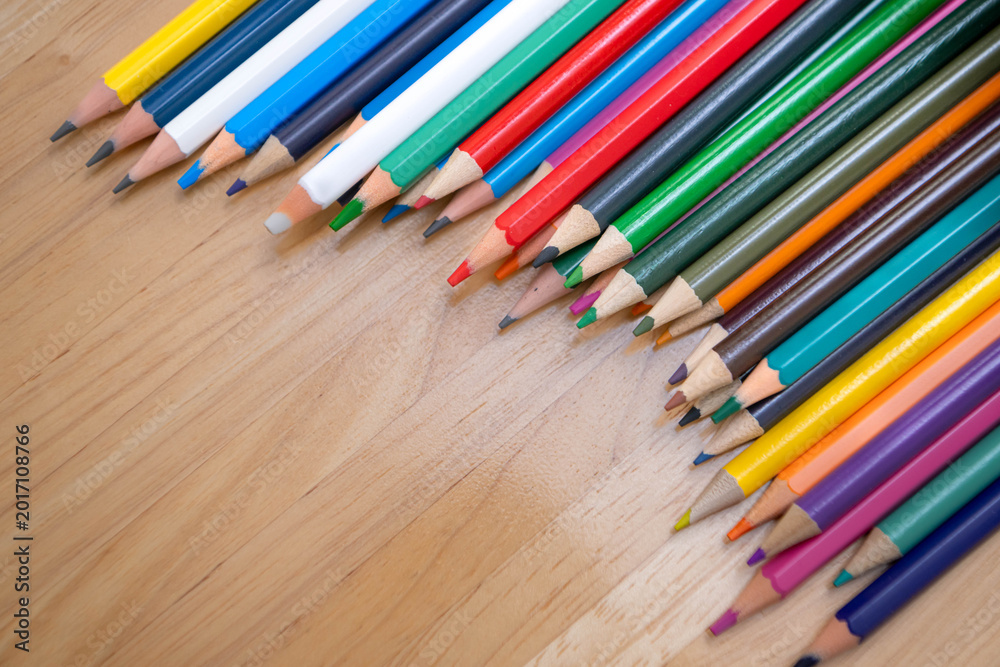 Fototapeta premium Top view of colorful pencils lined on a wooden surface for education