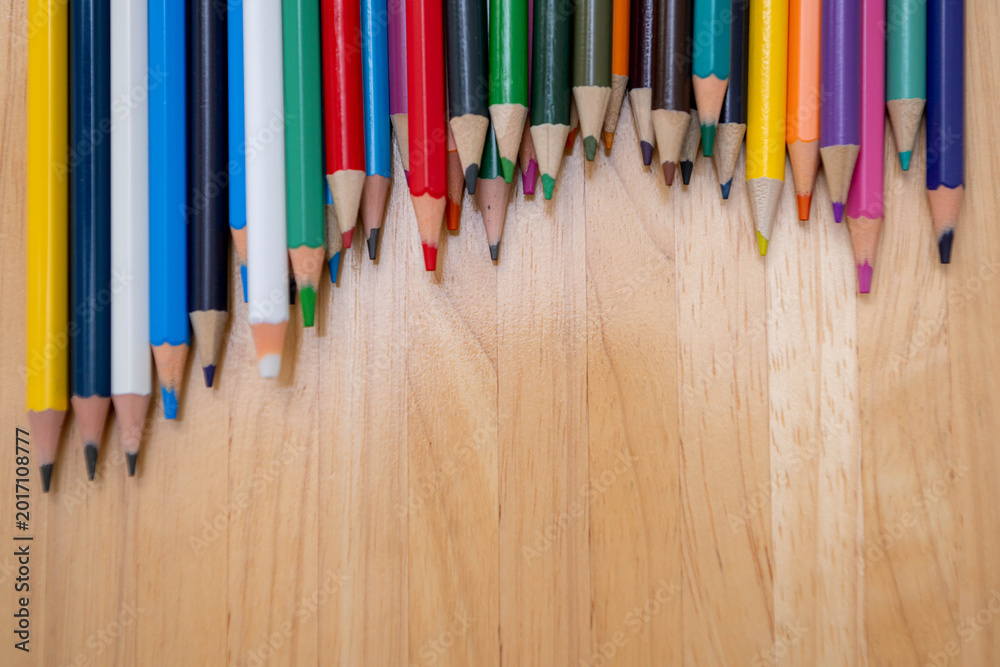 Fototapeta premium Top view of colorful pencils lined on a wooden surface for education