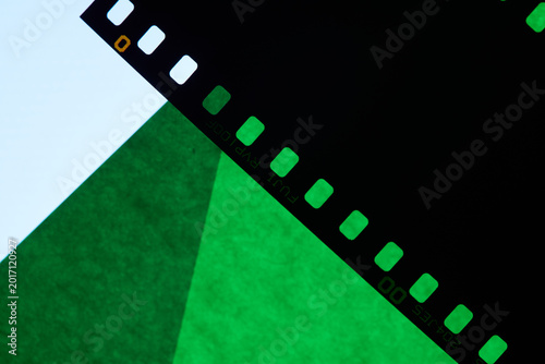 cinematic abstract background featuring vintage photographic film with visible perforation edges arranged in an artistic composition against a dark backdrop. Black and translucent green film strips 