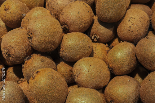 Fotografie Pile of brown fuzzy kiwifruit showing skin texture close up