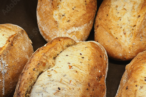 Bild auf Leinwand Freshly baked rustic multigrain bread loaves with seeds on dark surface