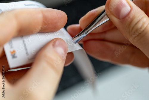 Hands taking and applying letter stickers with tweezers on English keyboard, Cyrillic alphabet characters for multilingual typing