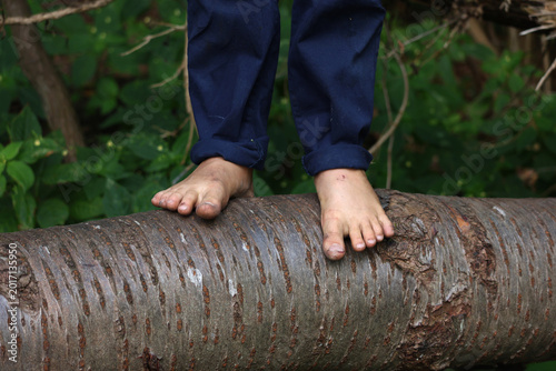 A childs feet on a tree log