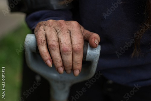 Photos A woman's dirty hand rests on the handle of a shovel outside in her garden