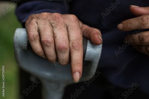 Photos A woman's dirty hand rests on the handle of a shovel outside in her garden