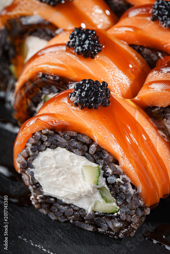 Slika na platnu Close up salmon topped black rice sushi rolls with caviar